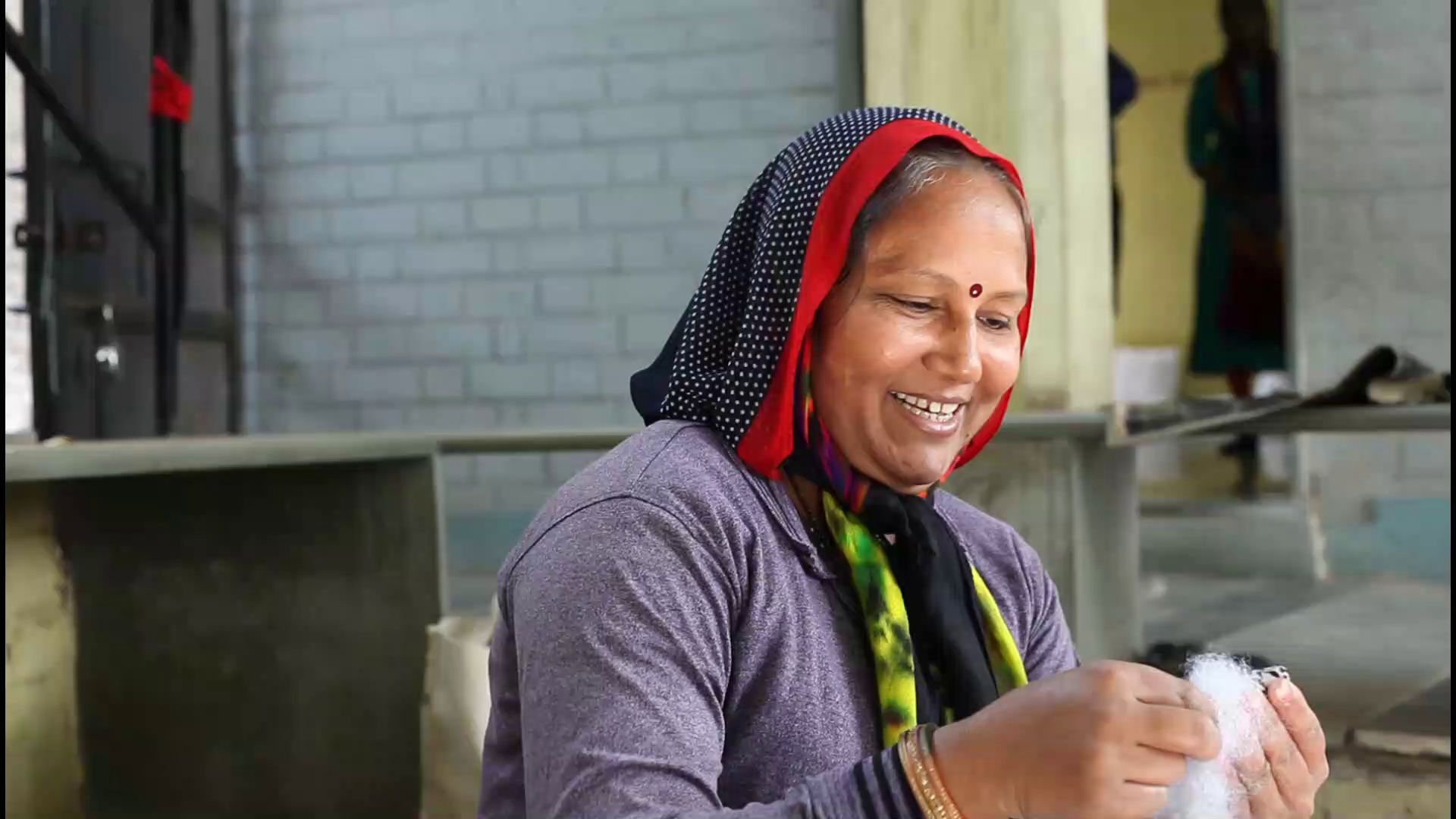 A Gramshree artisan smiling as she works on her craft
