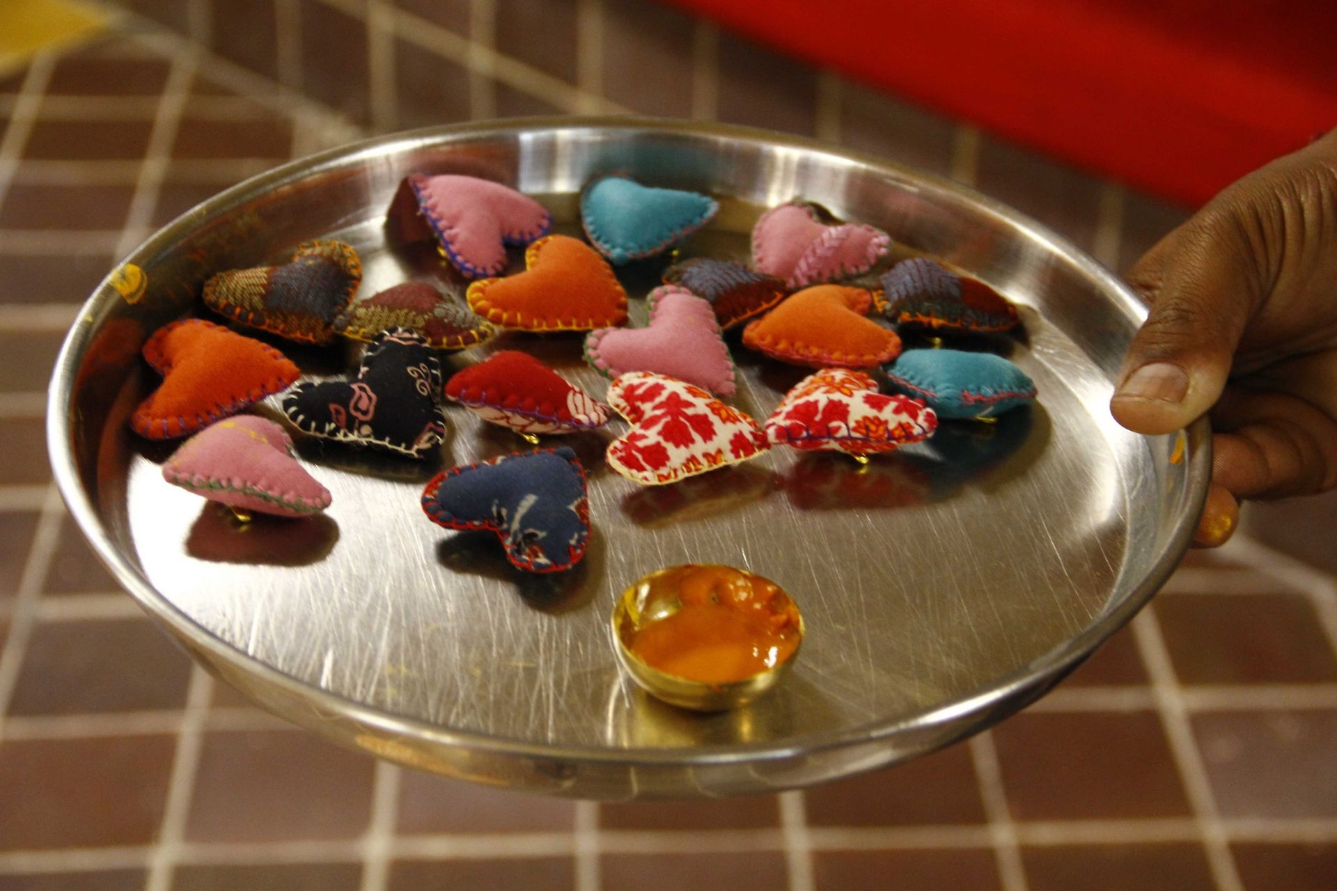 A plate of colourful handmade fabric heart pins made by Gramshree artisans